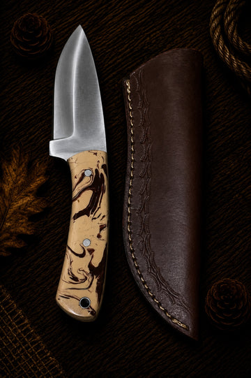 Fixed blade hunting knife with orange and green layered wood handle and embossed leather sheath